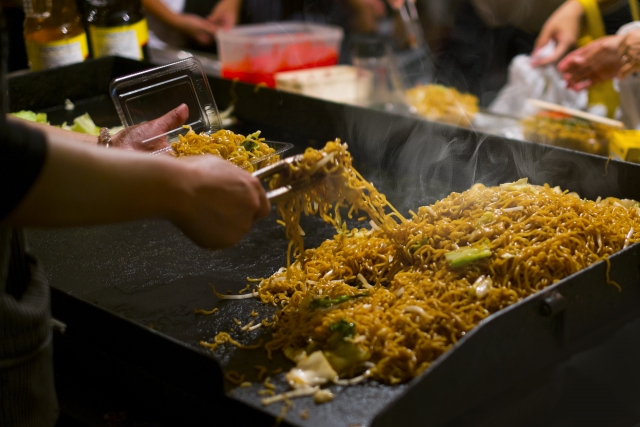 flat top grill frying yakisoba at a festival